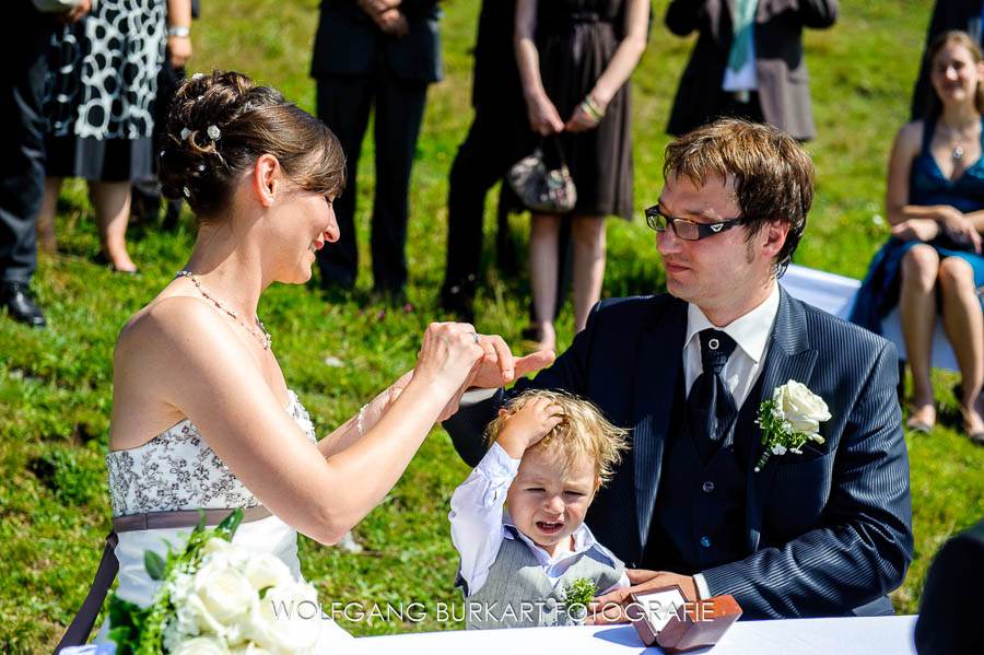 Hochzeit Fotograf Chiemsee, Brautpaar mit Kind beim Ringwechsel
