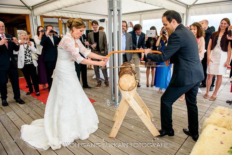 Hochzeit Fotograf in Tirol, Brautpaar beim Baumstamm sägen