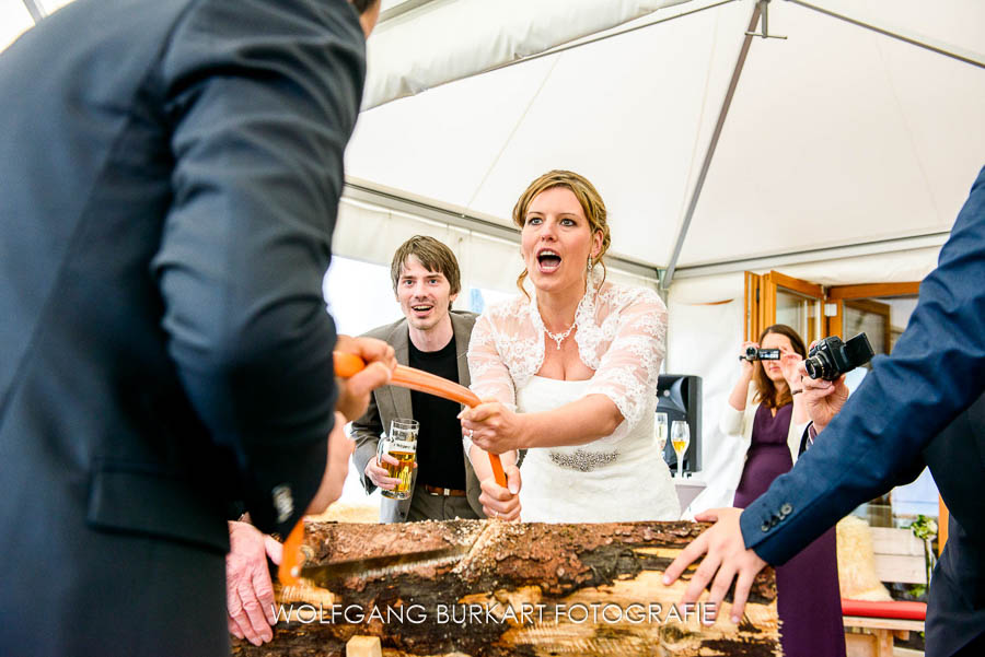 Hochzeit Fotograf Kitzbühel in Tirol, Brautpaar beim Baumstamm sägen