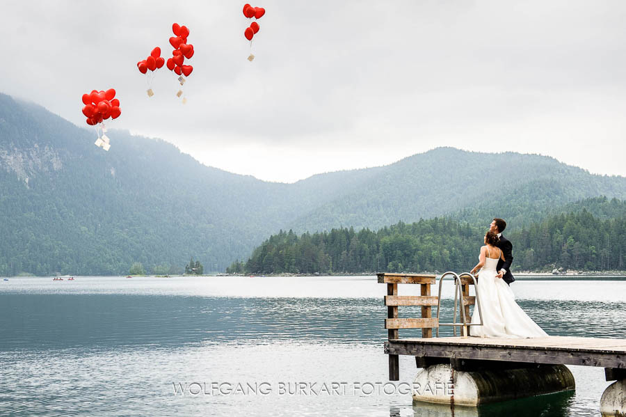 Hochzeits-Fotografie Garmisch Partenkirchen, Brautpaar lässt Luftballons fliegen am Eibsee