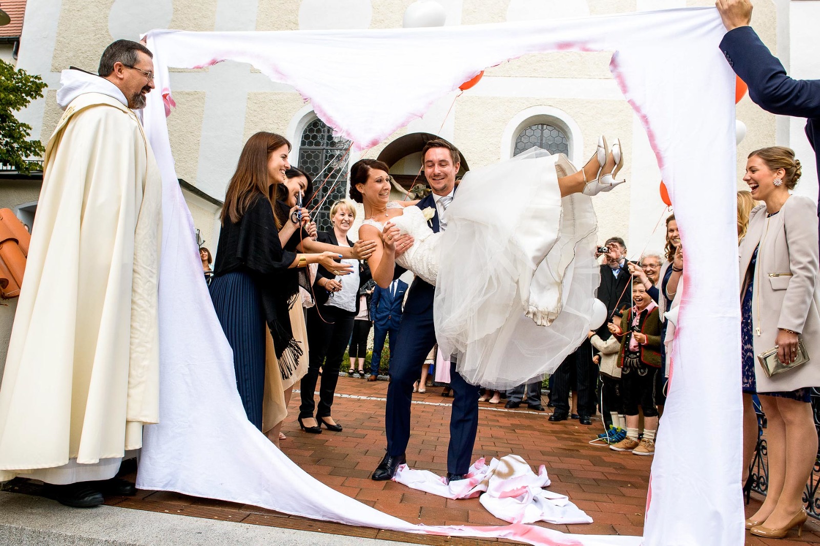 Hochzeitsfotografie München, Bräutigam trägt seine Braut durch das Bettlaken-Herz