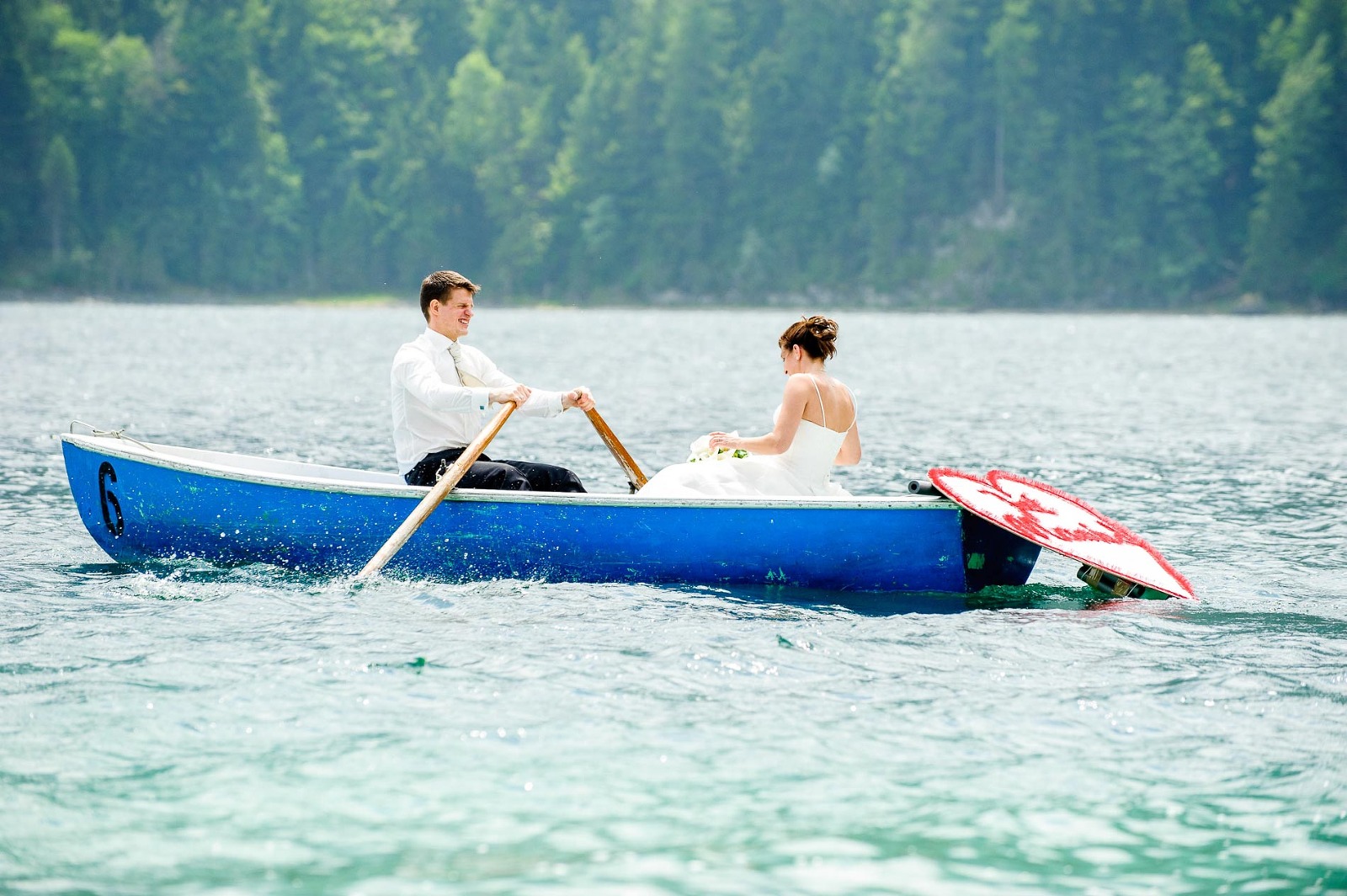 Fotograf Garmisch Partenkirchen Hochzeit, Bräutigam rudert seine Braut zur Maximiliansinsel im Eibsee