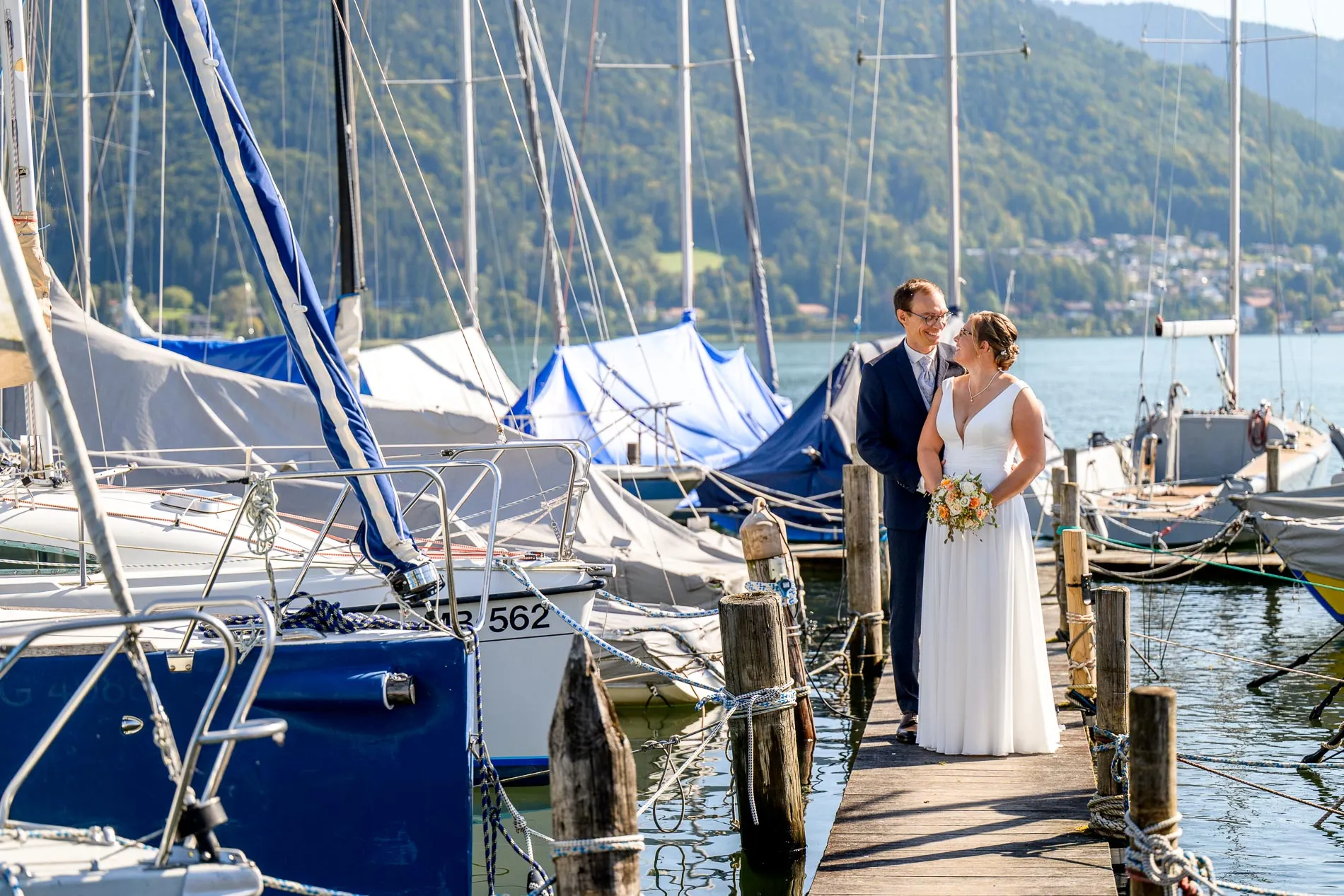 Brautpaar-Shooting am Tegernsee: Romantisches Foto des Paares auf einem Steg in Bad Wiessee an einem sonnigen Tag.